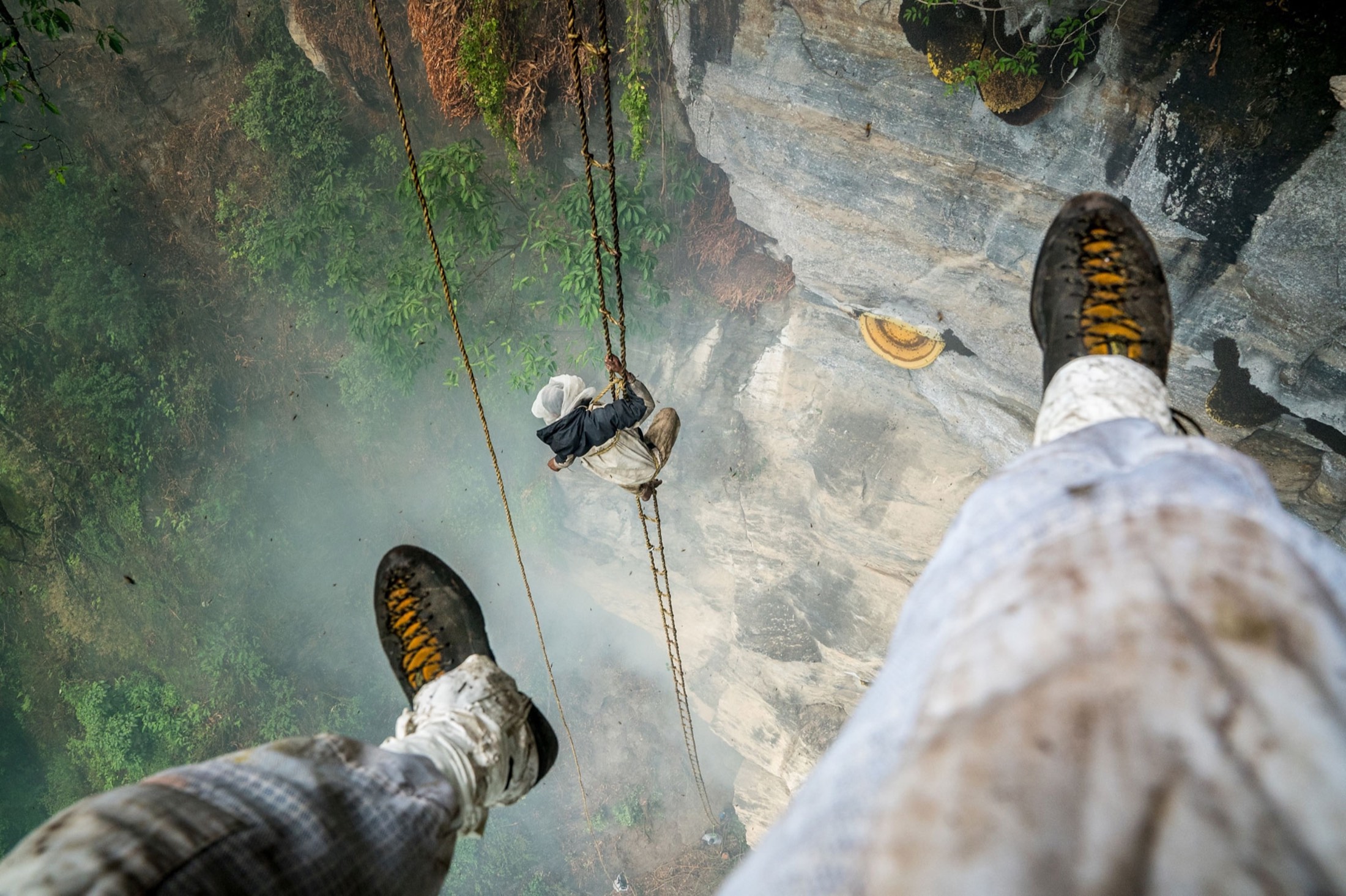 Looking straight down past a hunter's own boots to a colleague far below on the rope ladder